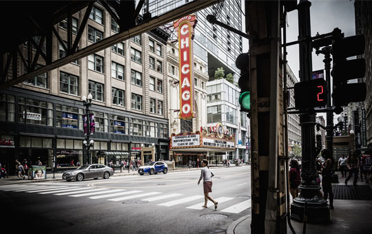 Person jogging across State Street with the Chicago Theatre in the background
